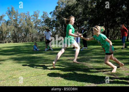 Handover of baton in relay race. Primary school sports day in Australia. Stock Photo
