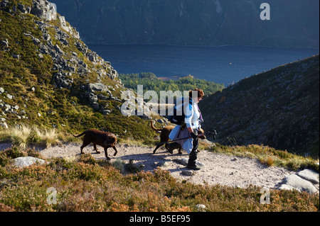 Loch Muick nr Spittal of Glenmuick Woman walking dogs on lead in mountains of Scotland UK in the autumn Stock Photo