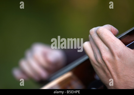 20s mans hands playing guitar outdoors pressing strings on frets Stock Photo