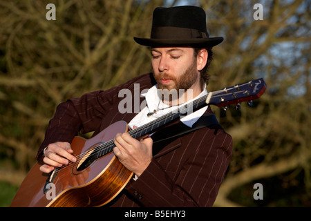 bearded 20s man playing guitar outdoors Stock Photo