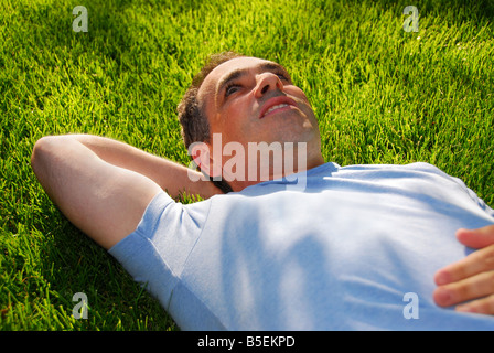 Attractive man lying on green grass in a park relaxing Stock Photo