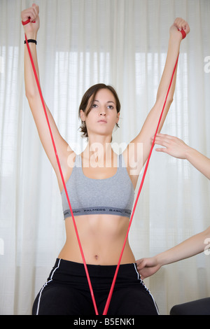 young woman doing exercises with theraband sitting on exercise ball Stock Photo