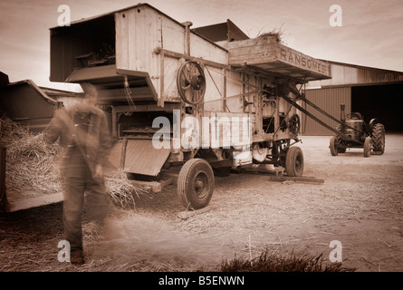 Old working machinery from past times in sepia. A Threshing Drum driven by a Feild Marshall Tractor Stock Photo