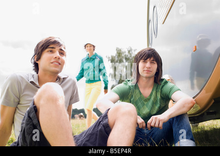 Germany, Leipzig, Ammelshainer See, Young men sitting near camping trailer Stock Photo