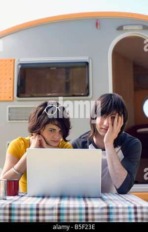 Germany, Leipzig, Ammelshainer See, Young couple sitting by camping trailer using laptop Stock Photo
