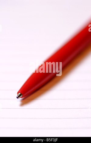 Red biro pen on lined paper close up Stock Photo