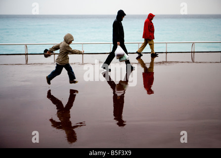 Tourists brave the rain on the Promenade des Anglais Nice France Stock Photo