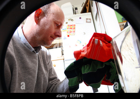 Middle age man loading dirty clothes washing into a washing machine view from inside Stock Photo