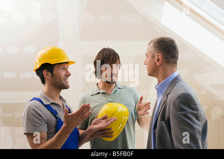 Two men talking to Architect at Construction Site Stock Photo