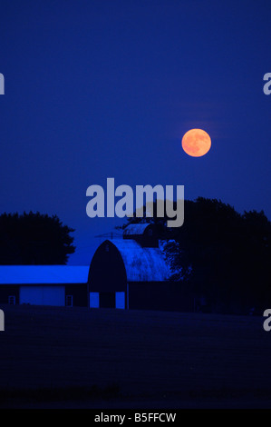 A full moon rises over a farm in the Midwestern USA Stock Photo