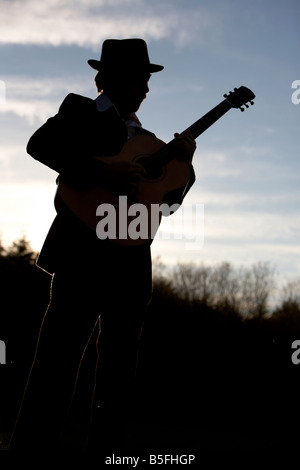 bearded 20s man playing guitar outdoors Stock Photo