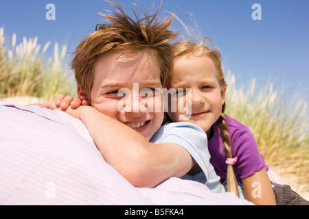 Germany, Baltic sea, Boy (8-9) and girl (6-7) in sand dunes, smiling, portrait, close-up