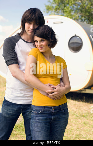 Germany, Leipzig, Ammelshainer See, Young couple embracing, in background camping trailer, portrait Stock Photo