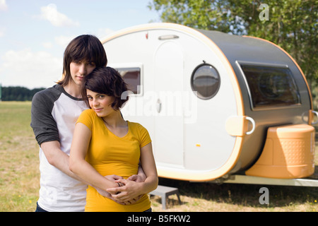 Germany, Leipzig, Ammelshainer See, Young couple embracing, in background camping trailer, portrait Stock Photo