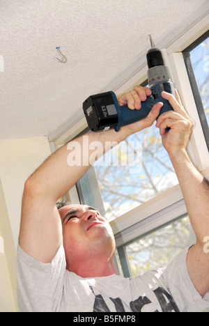 Man drilling a hole in a ceiling Stock Photo