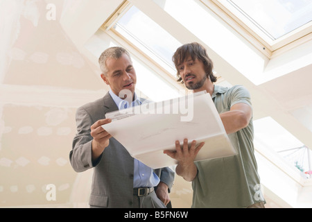 Two men looking at construction plan Stock Photo