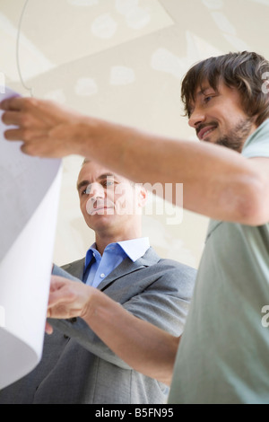 Two men looking at construction plan, smiling Stock Photo