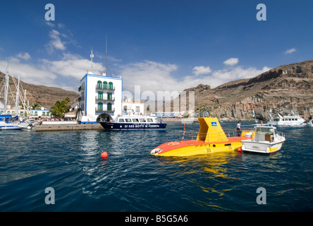 Yellow submarine tourist attraction in Puerto Mogan cruising with pilot boat to view marine life Atlantic Ocean off Gran Canaria coast Canary Isles Stock Photo