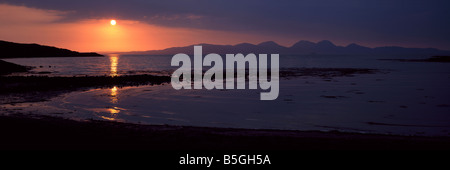 Panoramic landscape dramatic sunset over Paps of Jura Isle of Jura from Island of Gigha Argyll Hebrides west coast Scotland UK Stock Photo