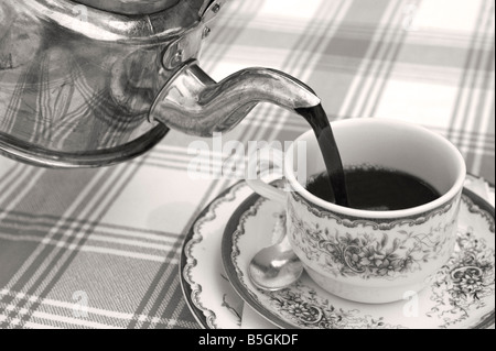 pour out filling up a cup with fresh hot black coffee from an old swedish coffe pot made out of copper b/w Stock Photo
