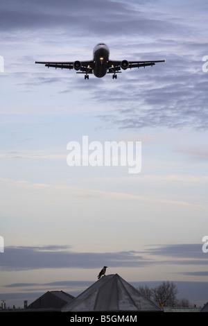 A plane flying over rooftops Stock Photo