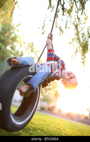 Four year old boy playing on tire swing Stock Photo