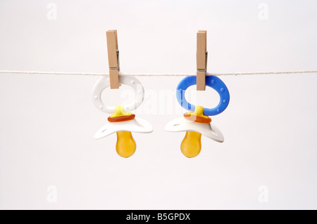 Colorful baby pacifiers hanging by clothespins on a clothesline Stock Photo