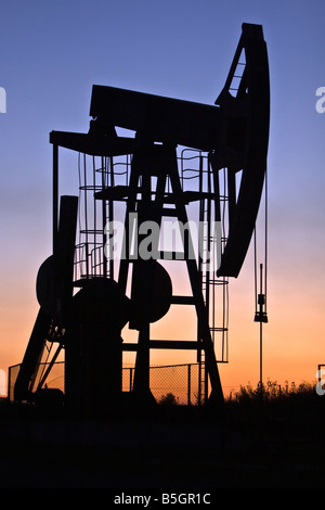 industrial pump jack in the sunset silhouette Stock Photo