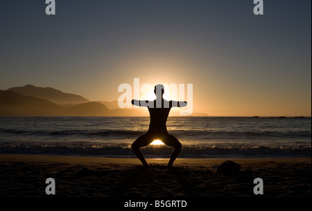 Man facing the sun doing yoga at early morning Trinidade Rio de Janeiro Brazil Stock Photo