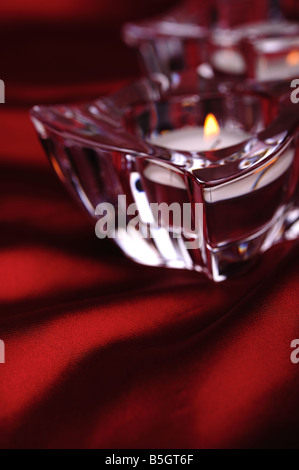 Pair of candles in a glass candlesticks red silk background Stock Photo