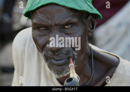 An elderly Dinka man smokes a traditional pipe in Rumbek, South Sudan Stock Photo