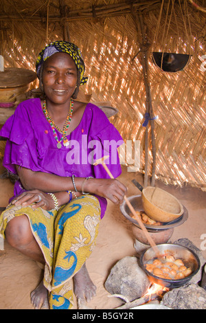 A woman in a small village in southwestern Niger cooks 'fari masas' inside her traditional straw house. Stock Photo