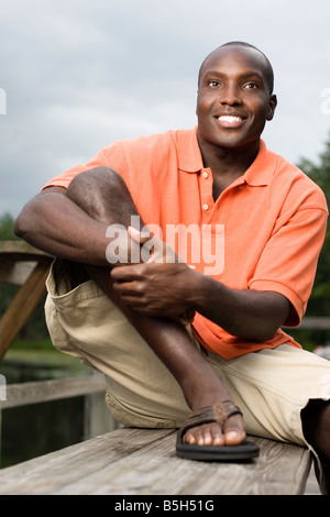 A young man smiles while sitting on a bench at a dock in Orlando, Florida. Stock Photo