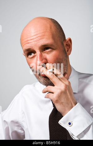 Man in white shirt and knitted tie smoking a cigarette Stock Photo