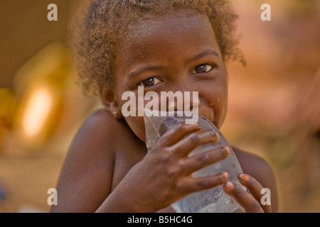 This Fulani girl in Ouagadougou, Burkina Faso pierces the bag with her teeth then enjoys the cool water. Stock Photo