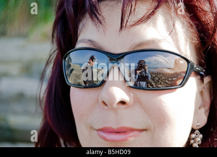 Reflection of two guys in sunglasses of a nice lady on the beach.