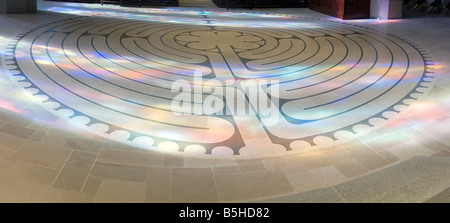 A circular stone labyrinth on the floor of Grace Cathedral is illuminated by colorful light patterns from nearby stained-glass windows. Stock Photo
