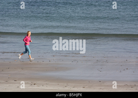 Blonde woman outdoors. Jogging along beach. Stock Photo
