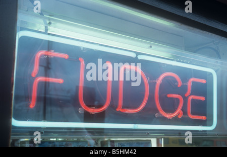 Lit neon sign set in perspex box hanging in shop window stating in red and white FUDGE Stock Photo