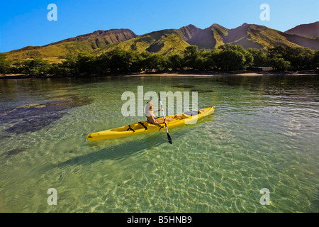 A young woman paddles a kayak at Olowalu, Maui, Hawaii. Stock Photo