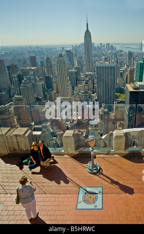 Tourists taking souvenir photographs of young couple on exterior viewing platform at the top of the Rockefeller Centre, New York Stock Photo
