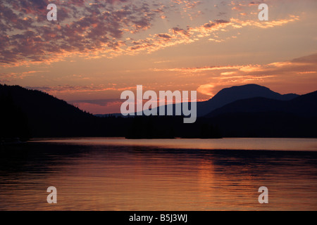 Dramatic sunset at Ruby Lake near Vancouver BC with coastal mountains in background and reflections in lake in July Stock Photo