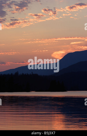 Dramatic sunset at Ruby Lake near Vancouver BC with coastal mountains in background and reflections in lake in July Stock Photo