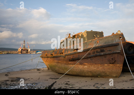 Beached rusty hulk, wrecks of a decaying ship and oil rig in Invergordon, Cromarty Firth, Scotland, UK Stock Photo