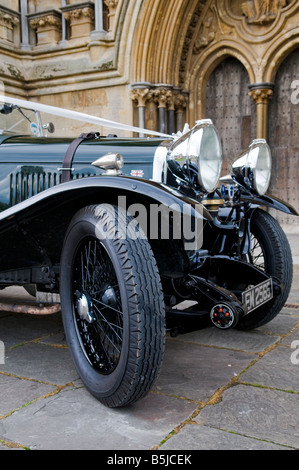 A renovated 1930's bottle green, Lagonda classic car with white ribbons waiting outside Wells Cathedral at a wedding. Stock Photo