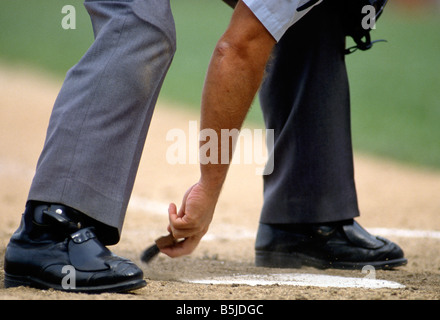 Umpire dusting off home plate Stock Photo