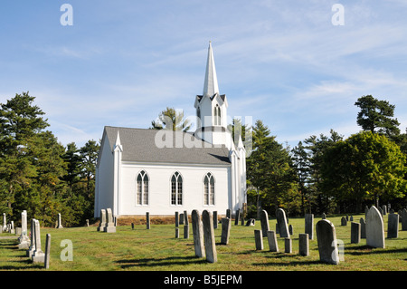 Old white New England church and steeple with graveyard and cemetery headstones. Stock Photo