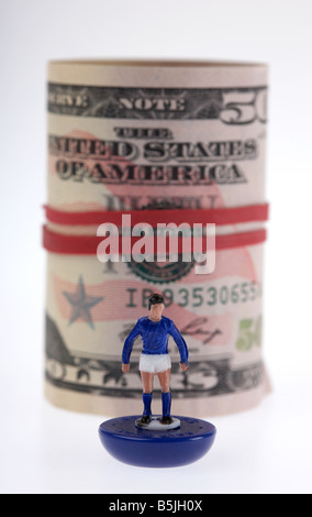 wad of 50 usa dollar bank notes cash tied up in a roll with elastic band behind toy footballer Stock Photo