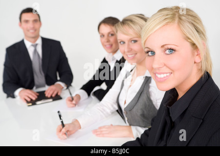 A businesswoman and a team of 2 women and a man out of focus behind her having a meeting Stock Photo