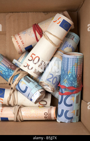 wads of 20 and 50 euro notes cash tied up in a rolls with elastic band hidden in a cardboard box Stock Photo